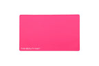 A hot pink rectangular beauty mat with rounded corners and the white text 'THE BEAUTY MAT' printed in the bottom-left corner, shown on a plain white background.