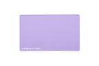 A lilac purple rectangular silicone beauty mat with rounded corners and the text 'THE BEAUTY MAT' printed in white in the bottom-left corner, shown on a solid white background.