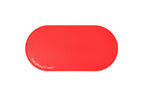A bright cherry red, oval-shaped silicone beauty mat with rounded corners, featuring the white text 'THE BEAUTY MAT' printed on the bottom-left edge, set against a plain white background.