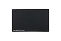 A black rectangular beauty mat with rounded corners and the text 'THE BEAUTY MAT' printed in white at the bottom left, shown on a plain white background.