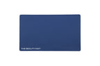 A rectangular navy blue beauty mat with rounded corners and the text 'THE BEAUTY MAT' printed in white at the bottom left, shown on a plain white background.